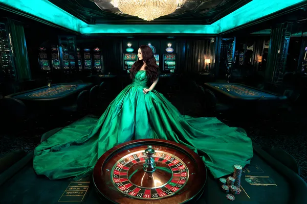 Uma mulher em um vestido verde luxuoso ao lado de uma roleta ornamentada, capturando o clima sofisticado do POPBEA.